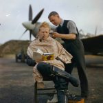 An RAF pilot getting a haircut while reading a book between mission